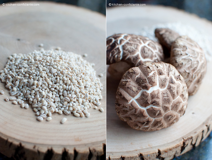 Image of a wooden board with uncooked pearl barley and shiitake mushrooms.