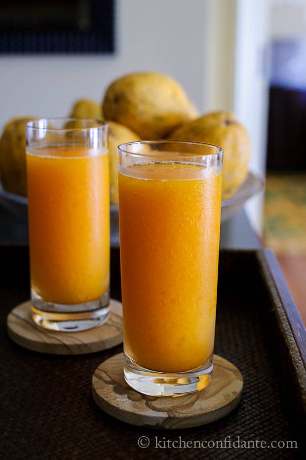 Two tall glasses filled with homemade bright orange papaya slushy. 