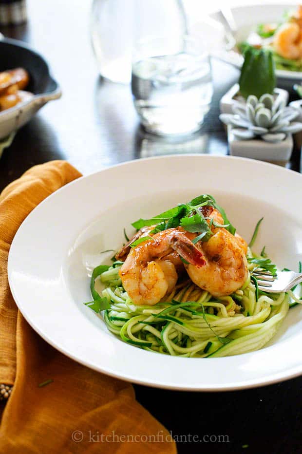 A pasta bowl full of zucchini noodles topped with shrimp.