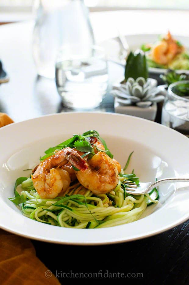 A pasta bowl full of zucchini noodles topped with shrimp.