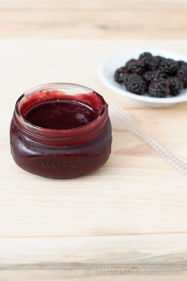 A small mason jar full of a deep red blackberry glaze.