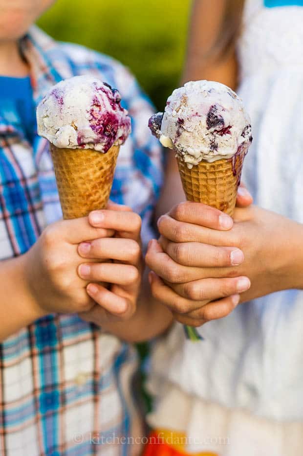 Two children hold ice cream cones, just starting to drip.