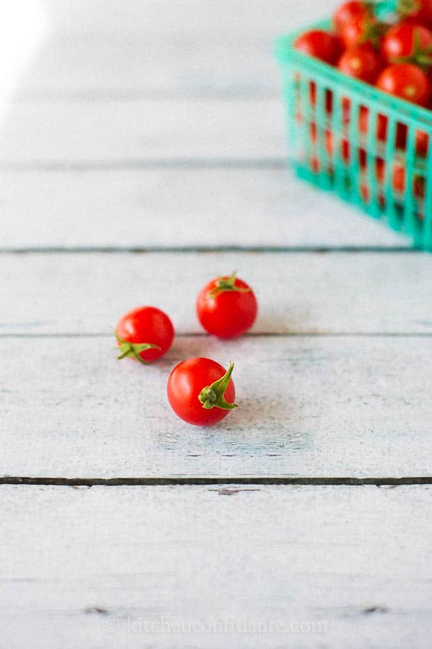 Three cherry tomatoes sit on a table ready to eat.