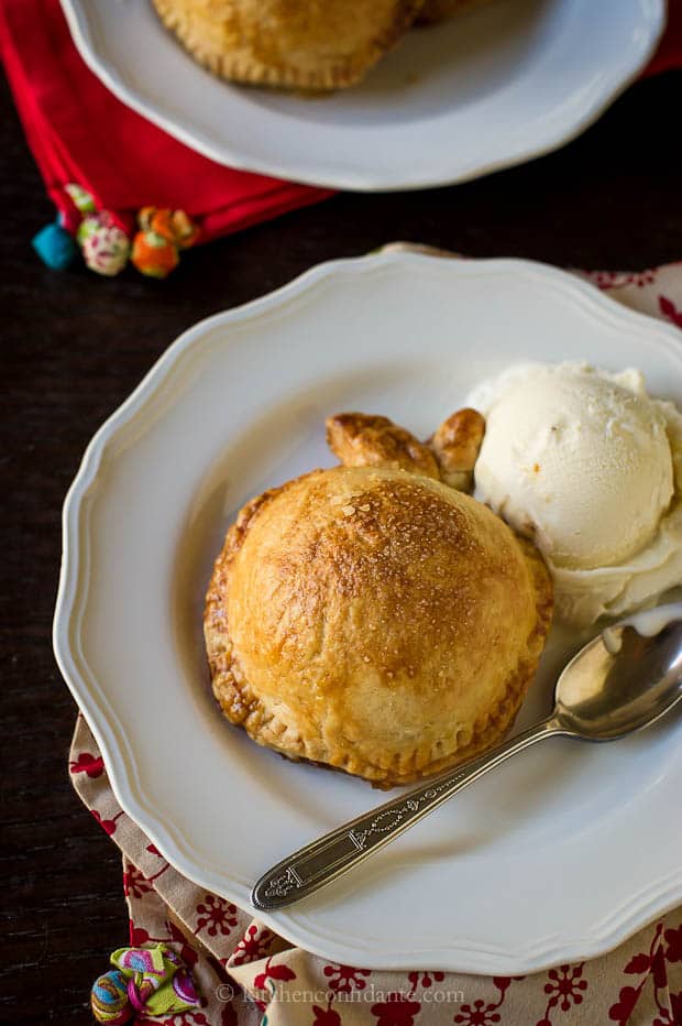 An apple dumpling sized for one, with a scoop of vanilla ice cream on a white plate.