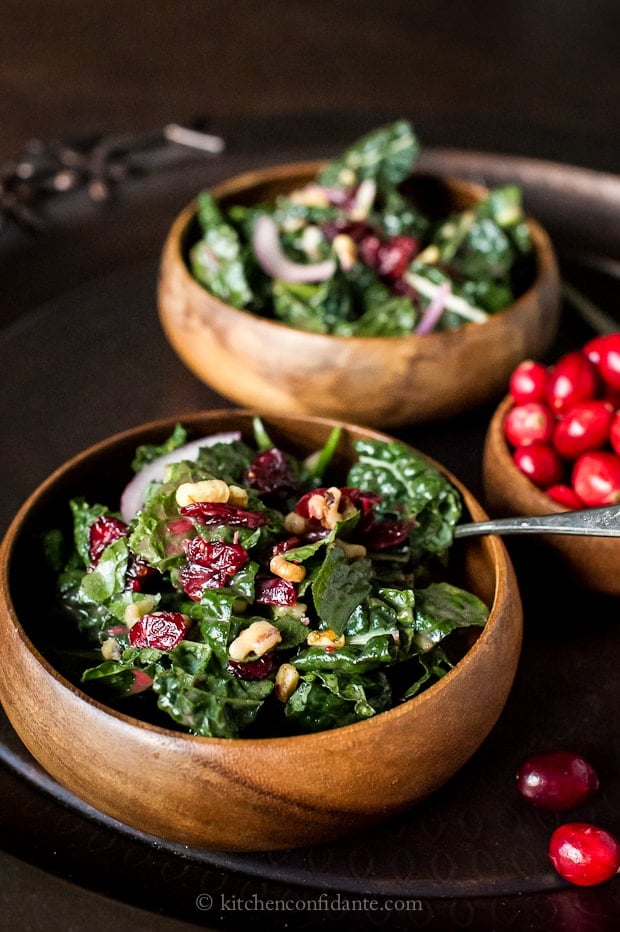 Cranberry Walnut Kale Salad in wooden bowls with fresh cranberries