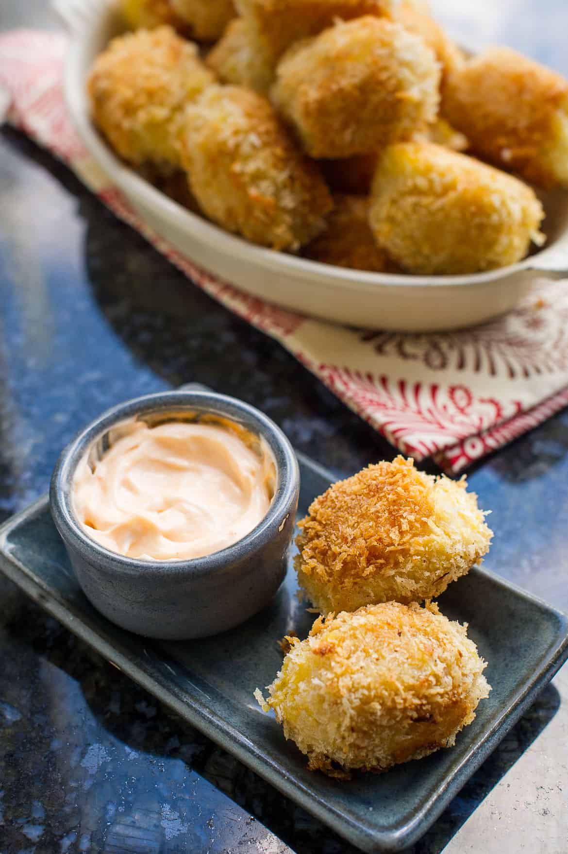 Shrimp and Potato Croquettes on a grey plate with a bowl of Sriracha Mayo.