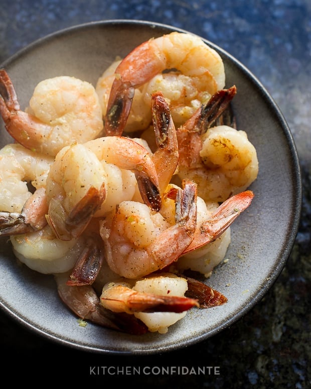 A gray bowl full of seasoned cooked shrimp.