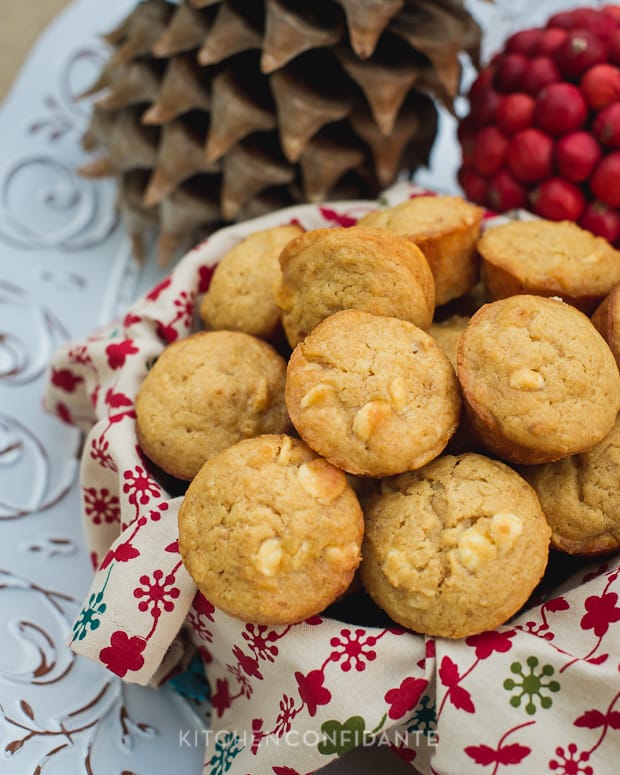 A bowl of White Chococolate Graham Cracker Muffins. A pinecone sits in the background, along with a red fruit.
