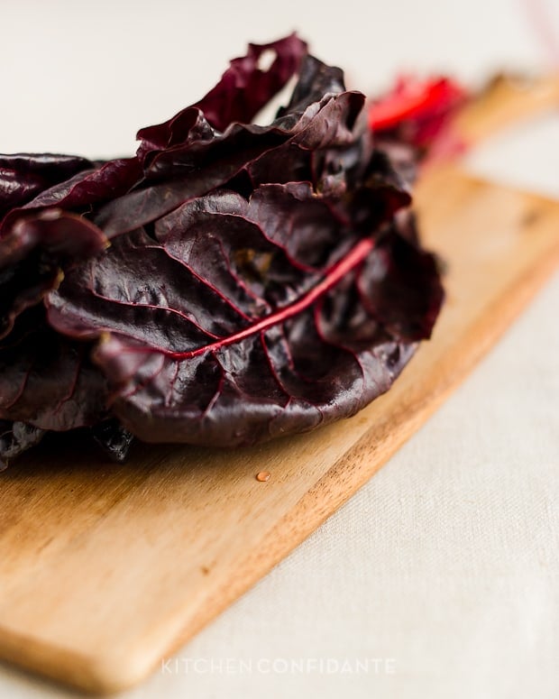 Red chard on a wooden cutting board.