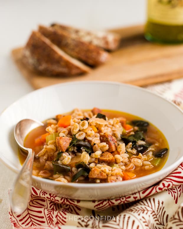 A spoon in a bowl of Farro Soup with Red Chard and Sausage.