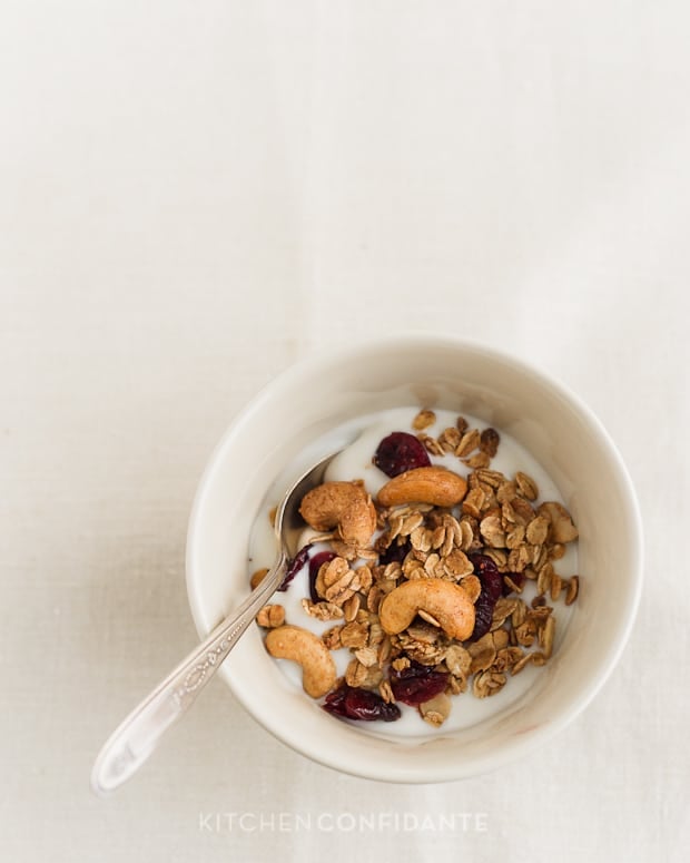 Granola with yogurt in a white bowl with a spoon.