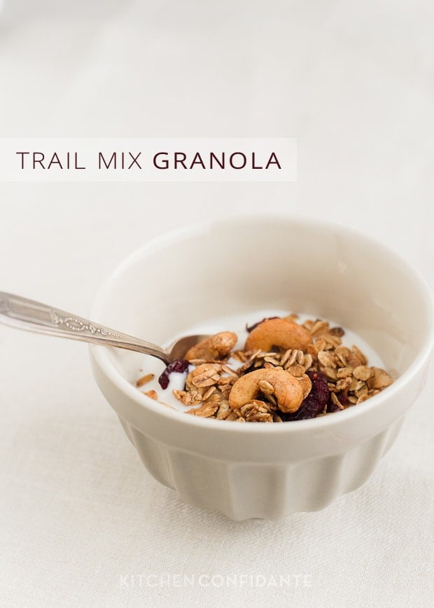 A small white bowl with yogurt and a topping of granola with the words, "Trail Mix Granola".