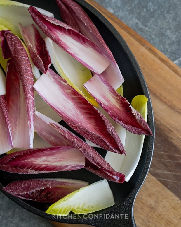 Green and red endive leaves in a cast iron dish.