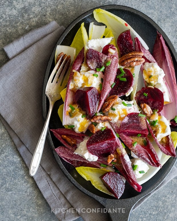 Beet and Burrata Endive Salad with candied pecans and Shallot Vinaigrette in a dish with a fork and napkin.