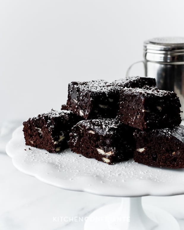 A stack of Fudge Jam Brownies on a white cake plate.