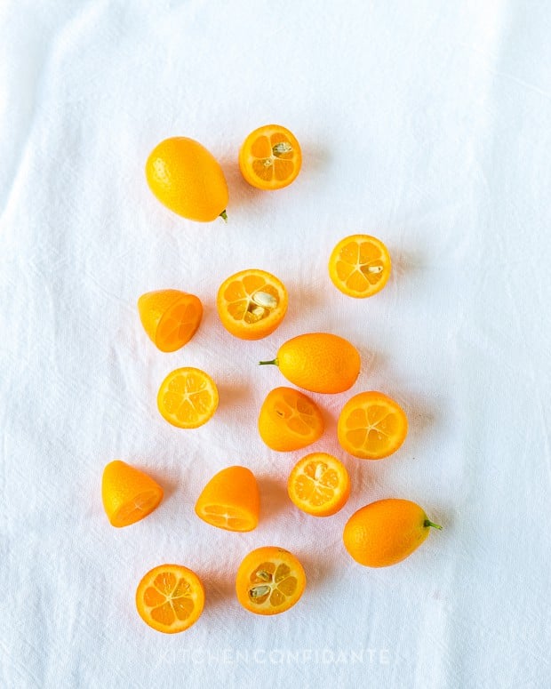 Whole and sliced kumquats on a white dishtowel. 