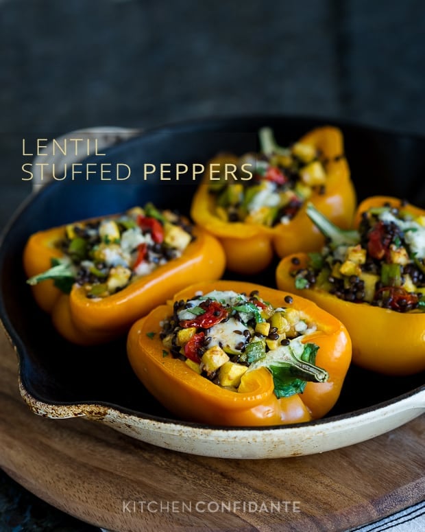 Four bell pepper halves stuffed with lentils, veggies, and cheese and then baked with the words, "Lentil Stuffed Peppers".