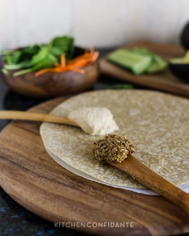 A whole grain tortilla with spoonfuls of whole grain mustard and hummus.