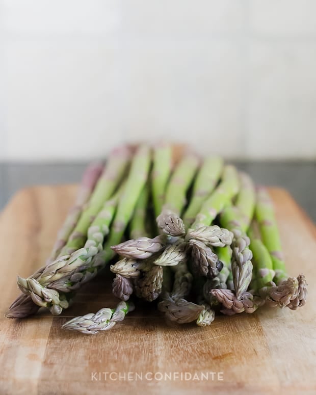 Stalks of asparagus on a wooden board.