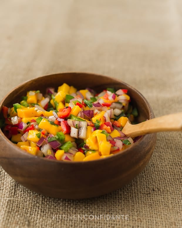 Mango Pepper Salsa in a wooden bowl with a wooden spoon.