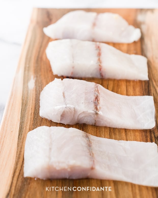 Raw sliced barramundi fillets on maple planks.