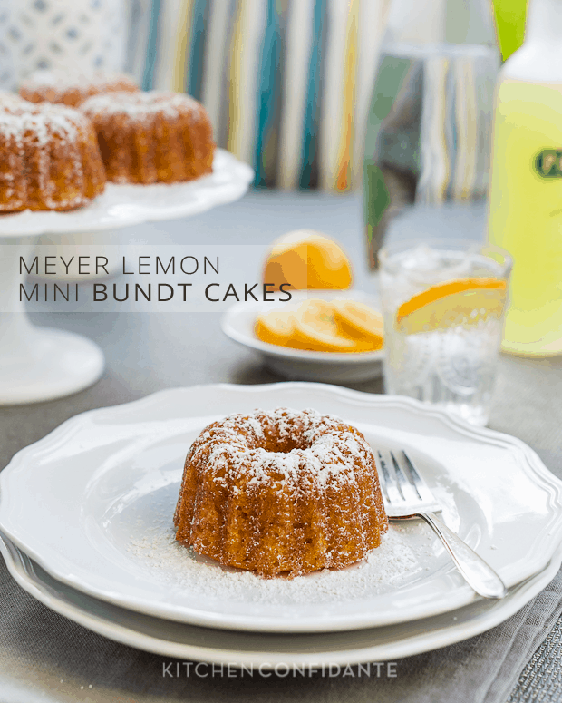 A Meyer Lemon Mini Bundt Cake served on a double stack of white plates with powdered sugar sprinkled on top.