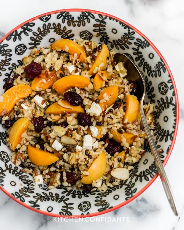 Wild Rice Salad with Apricots & Almonds and Apricot Dressing served in a colorful with a spoon.