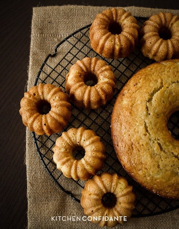 A full-size Bundt cake and mini Bundt cakes on a cooling rack.