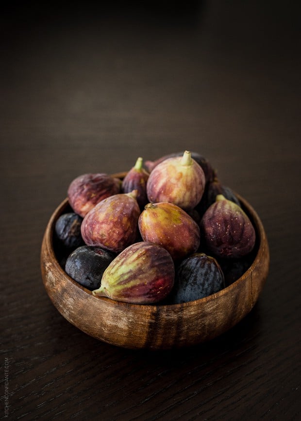 A wooden bow filled with fresh figs.