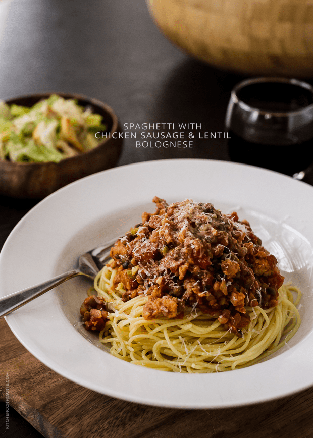 Spaghetti with Chicken Sausage and Lentil Bolognese in a white bowl with a fork.