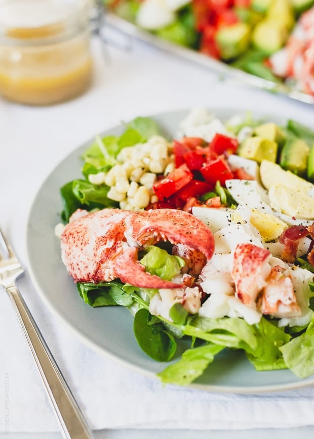 A plate of salad on a table beside a fork.