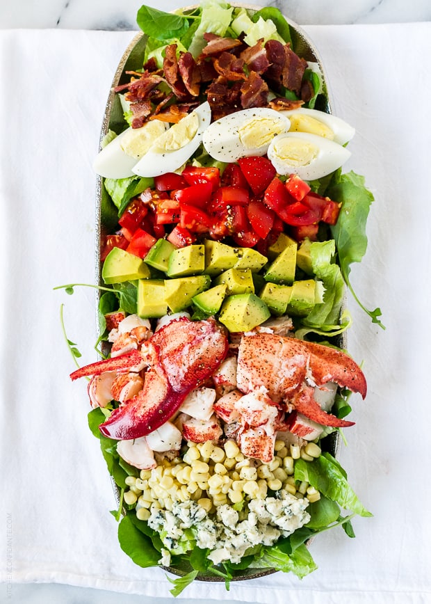 All of the ingredients of Lobster Cobb Salad laid out in neat rows on an oval platter.