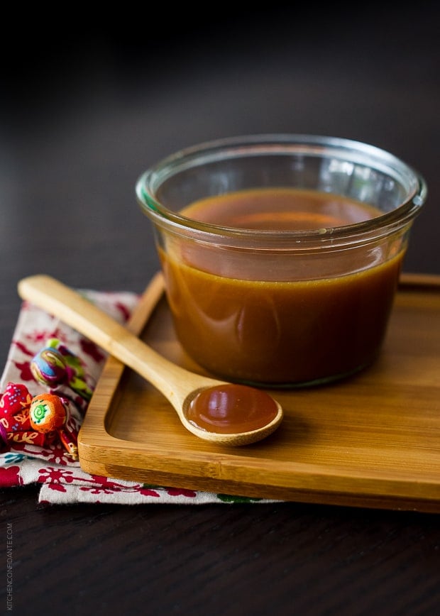 A wooden spoon and a glass dish of 10 Minute Microwave Salted Caramel Sauce.