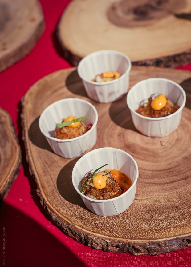 Live edge wooden rounds holding paper cups filled with tomato based appetizers.