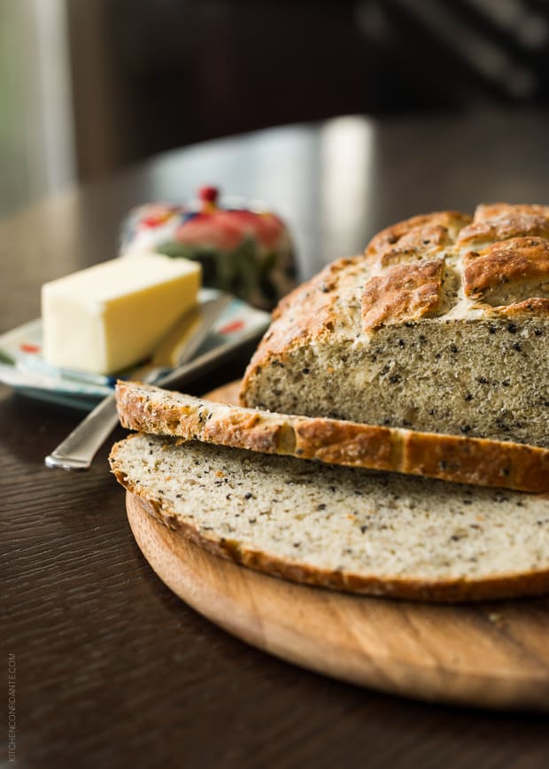 A loaf of bread sliced with a dish of butter in the background.