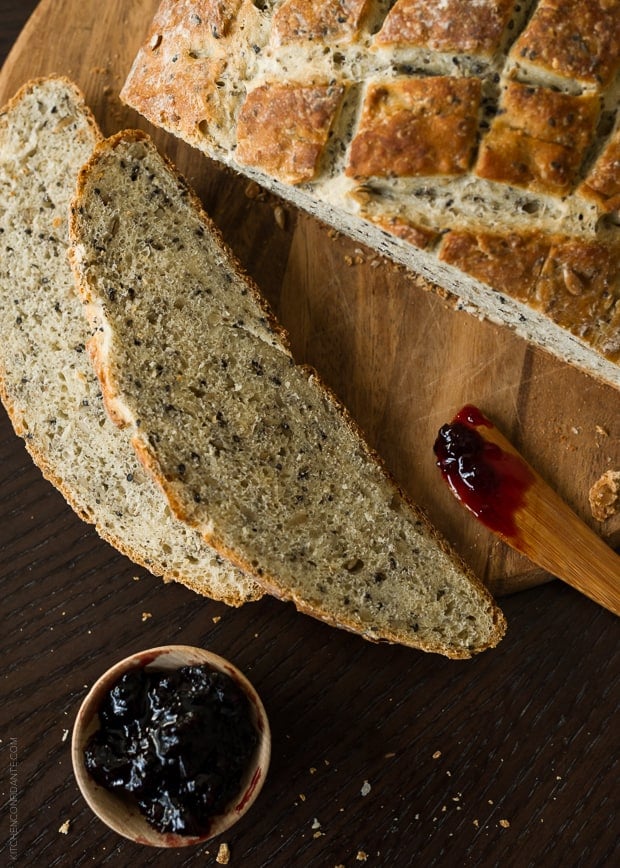 A loaf of sliced homemade bread and a dish of jam.