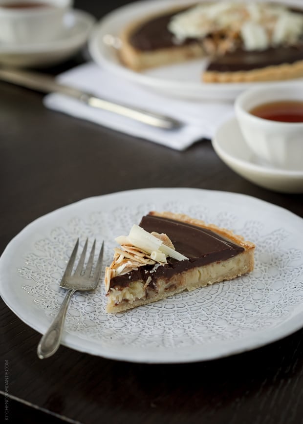 A slice of chocolate-topped coconut tart served on a plate with a fork.