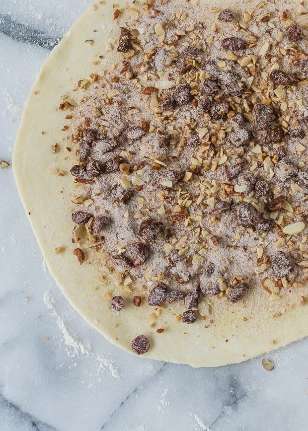 Dough for Rugelach rolled out and topped with nuts, sugar, and dried cranberries.