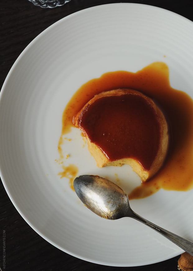 An individual Pumpkin Leche Flan being eaten on a white plate with a spoon.