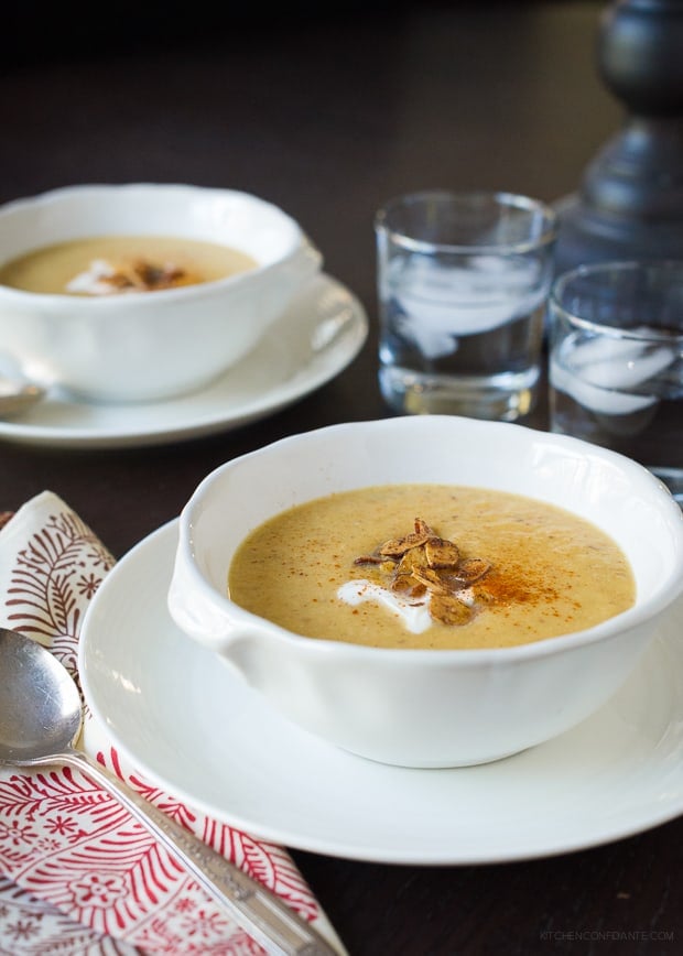 A bowl of Toasted Almond Butternut Squash Soup garnished with crème fraîche and toasted slivered almonds.