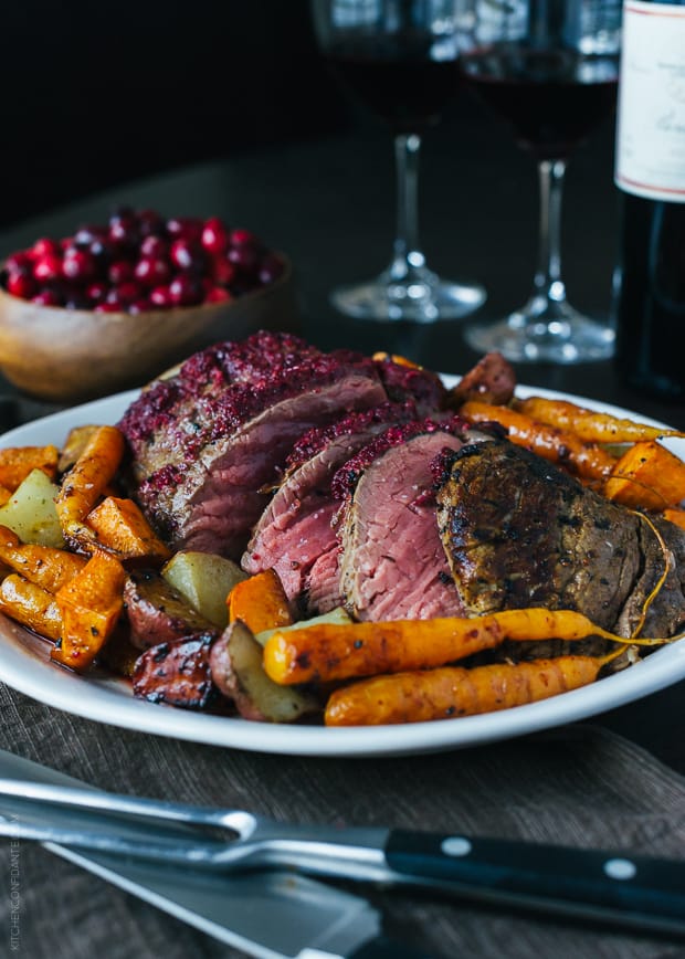 Cranberry Balsamic Crusted Chateaubriand surrounded by roasted carrots and potatoes.