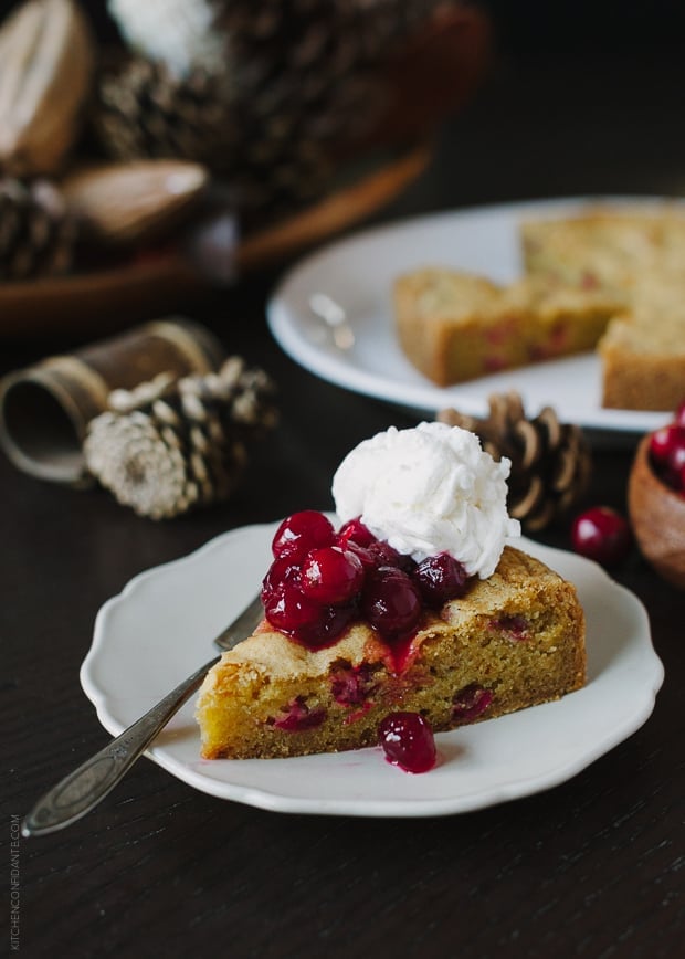 A slice of cranberry orange cake topped with cranberry sauce and whipped cream.