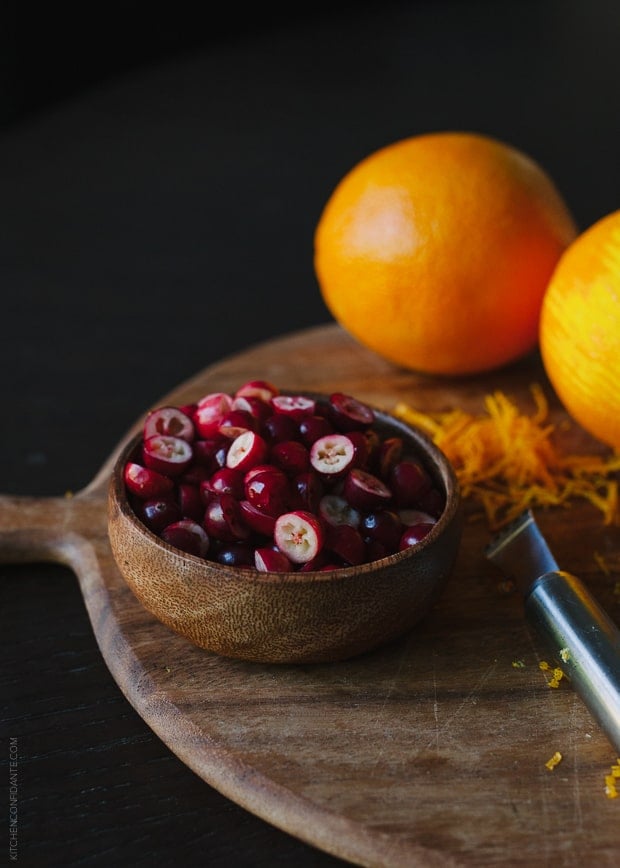 A bowl of cranberries and oranges.