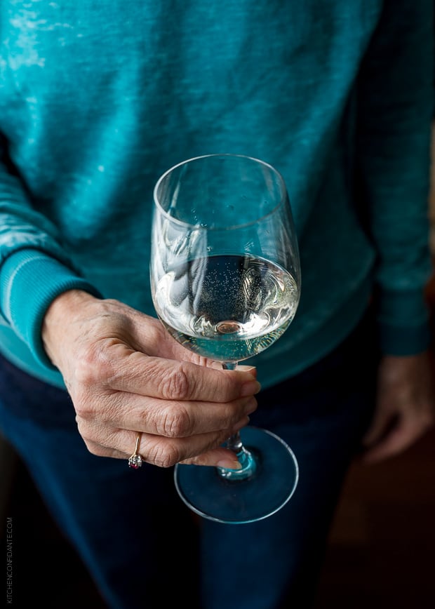 Woman in a blue sweater holding a glass of wine.