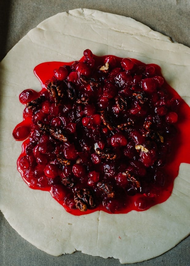 Spreading cranberry filling over a large piece of galette dough.