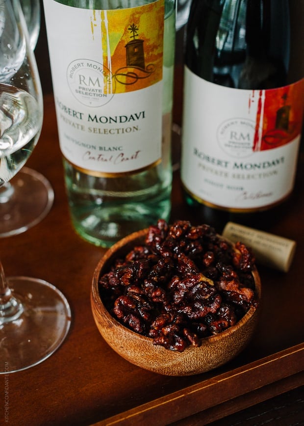 Candied walnuts in a bowl and bottles of wine.