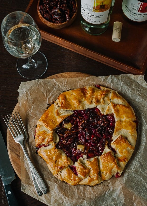 A rustic cranberry galette on parchment with two forks.