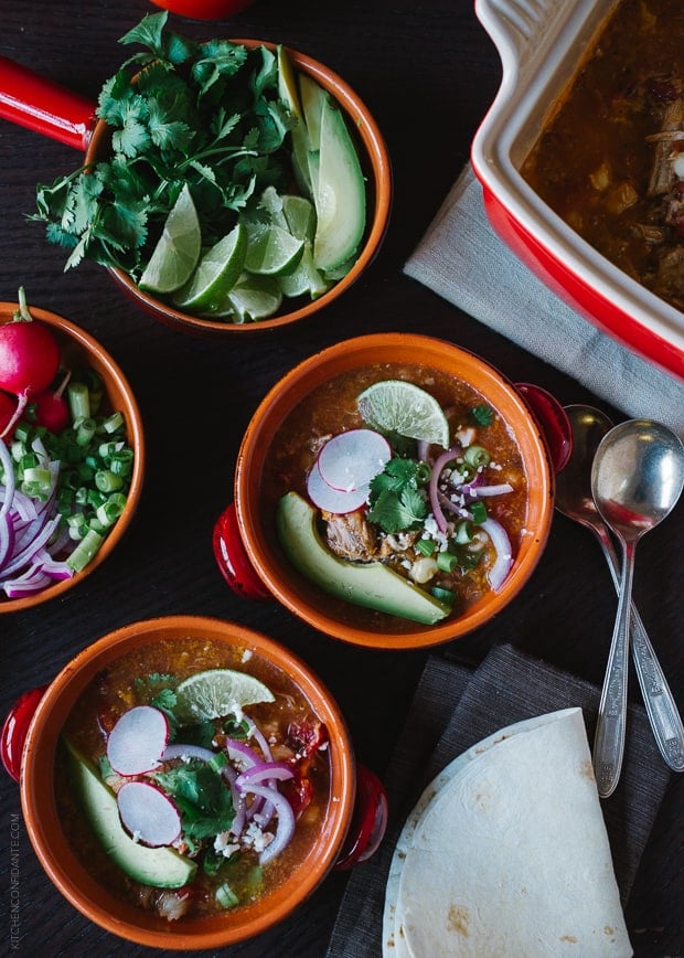 Bowls of Fire Roasted Chipotle Posole topped with slices of avocado, lime, and red onion.