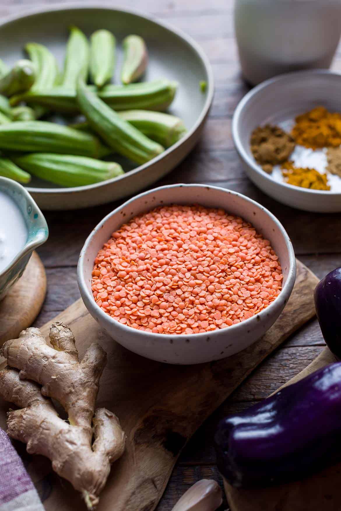 A wooden bowl filled with dried red lentils.