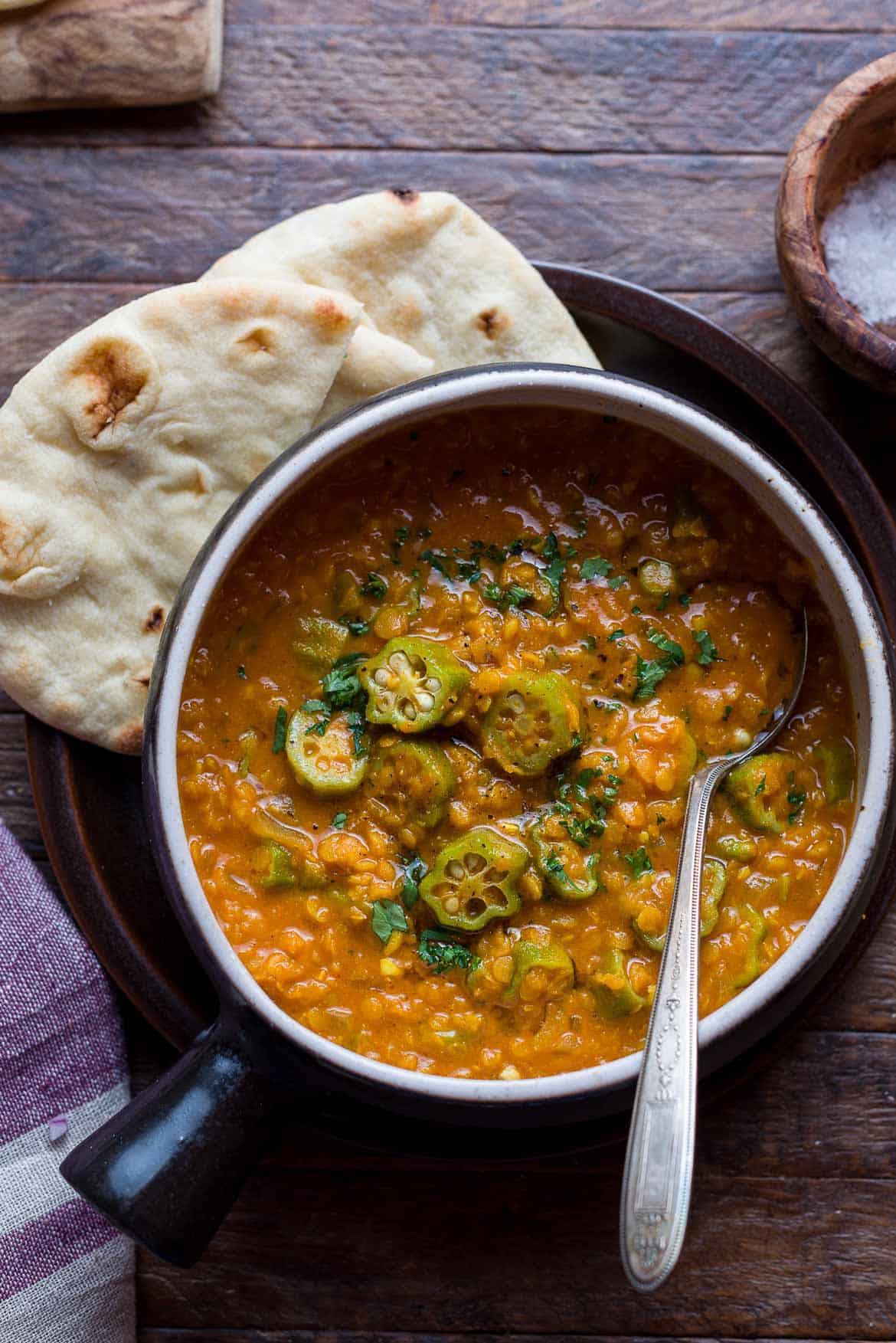 A bowl of Lentil Okra Curry with a spoon and piece of naan.